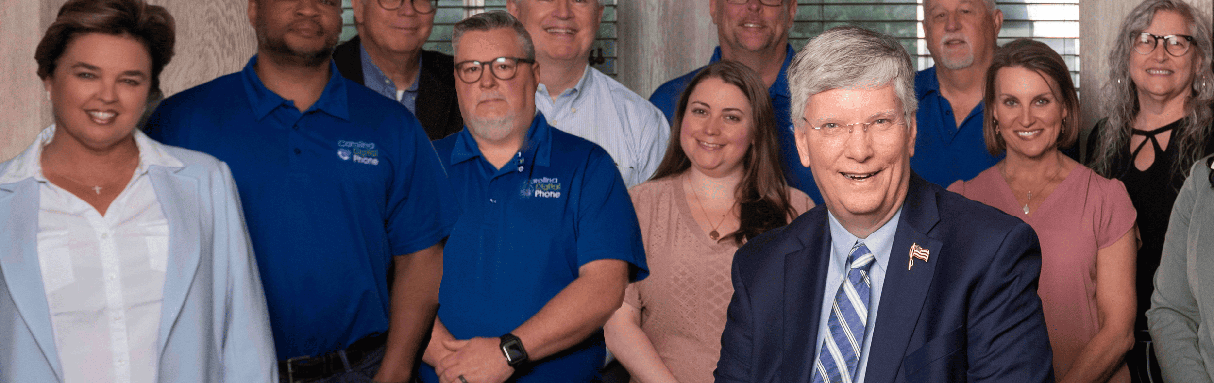 The Carolina Digital Phone team standing together in their downtown Greensboro office, with founder Nicky Smith in front