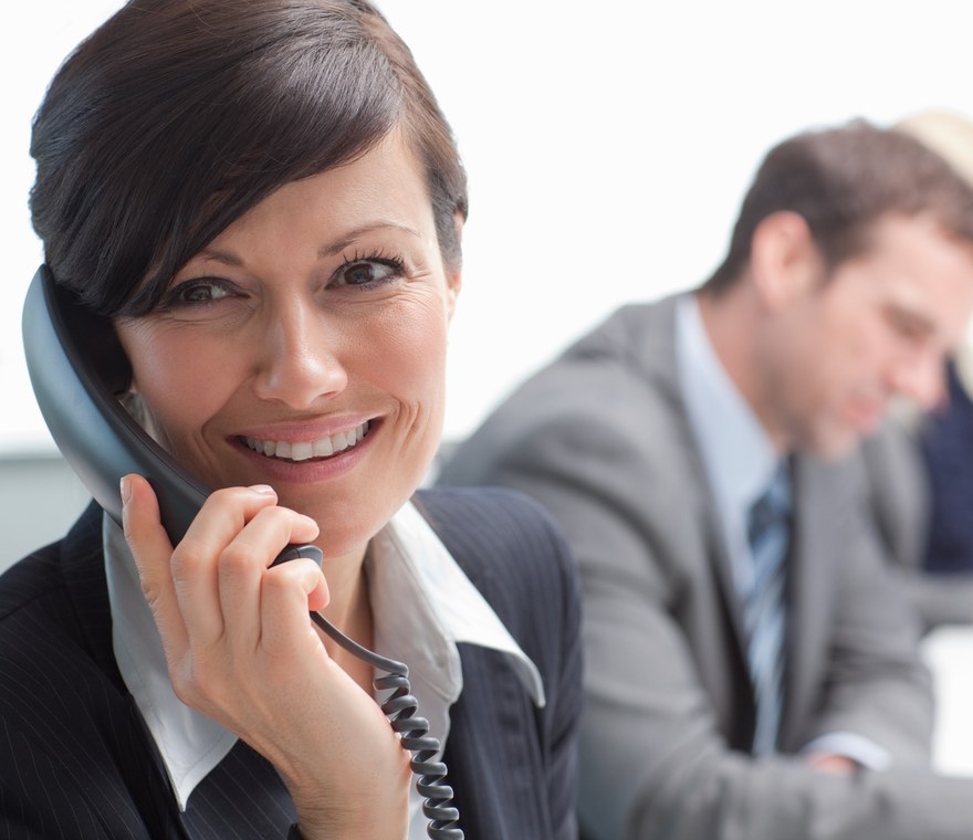 A small business employee smiling while talking on a business phone