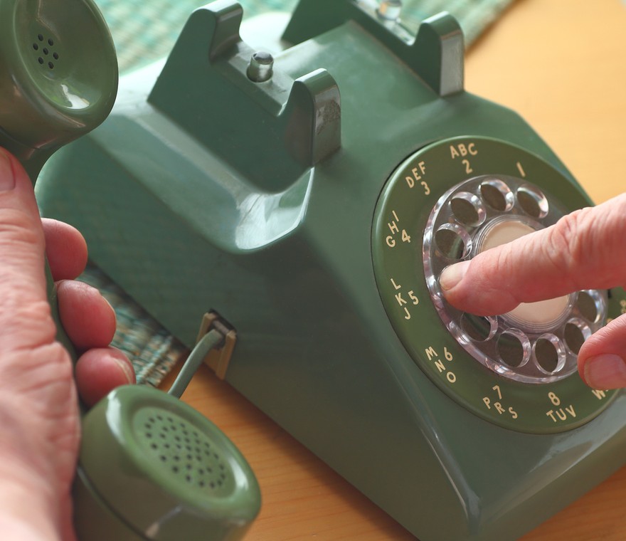 A person dialing a classic telephone