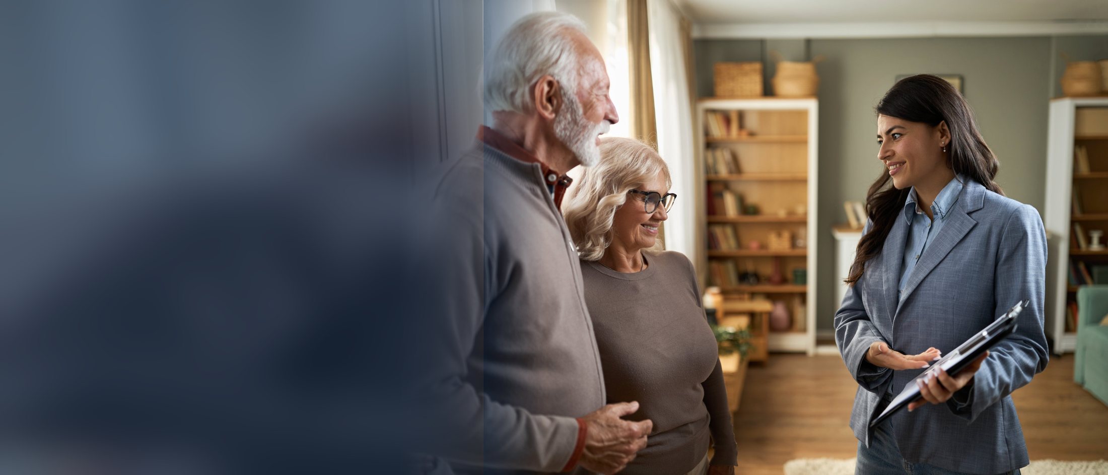 A property manager holding a clipboard and talking with an older couple inside a home